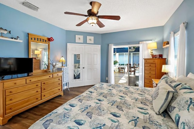 bedroom with dark wood-type flooring, a textured ceiling, ceiling fan, and a closet