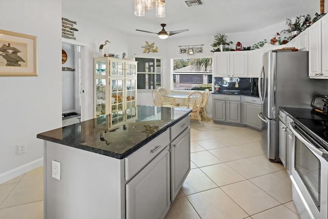 kitchen featuring a center island, tasteful backsplash, electric range, white cabinets, and ceiling fan