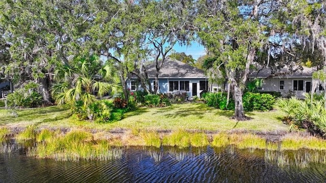 back of property with a lawn and a water view