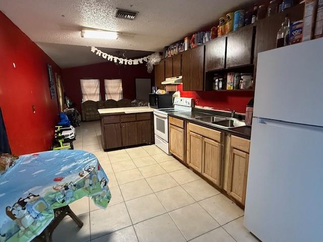 kitchen featuring light tile patterned flooring, white appliances, sink, and a textured ceiling