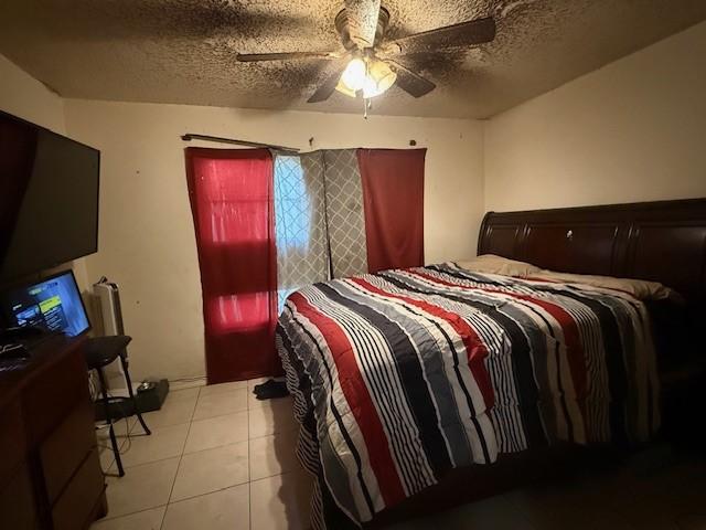 tiled bedroom with ceiling fan and a textured ceiling