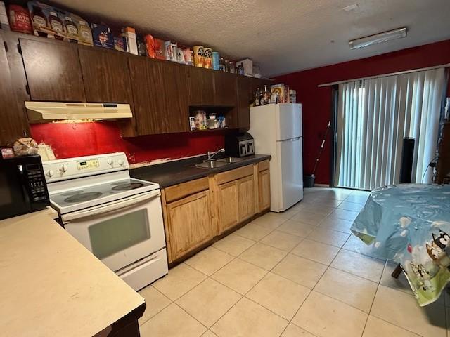 kitchen with white appliances, sink, a textured ceiling, and light tile patterned floors