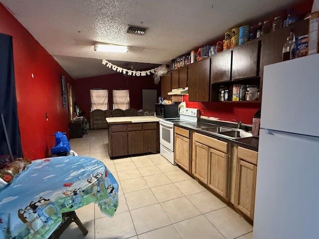 kitchen featuring sink, light tile patterned floors, white appliances, kitchen peninsula, and a textured ceiling