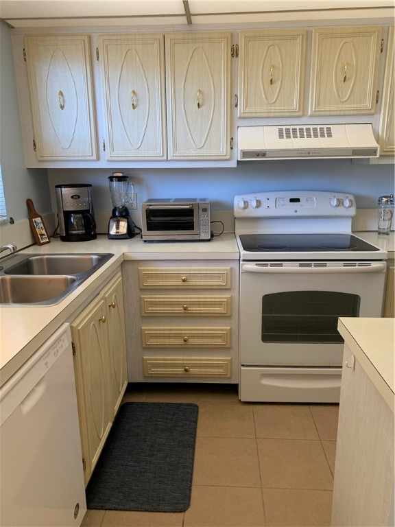 kitchen with sink, light brown cabinets, light tile patterned floors, white appliances, and ventilation hood