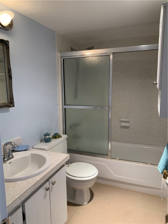 full bathroom with tile patterned flooring, shower / bath combination with glass door, toilet, and vanity