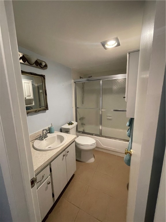 full bathroom featuring toilet, vanity, tile patterned flooring, and enclosed tub / shower combo