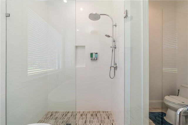 bathroom featuring a tile shower and toilet