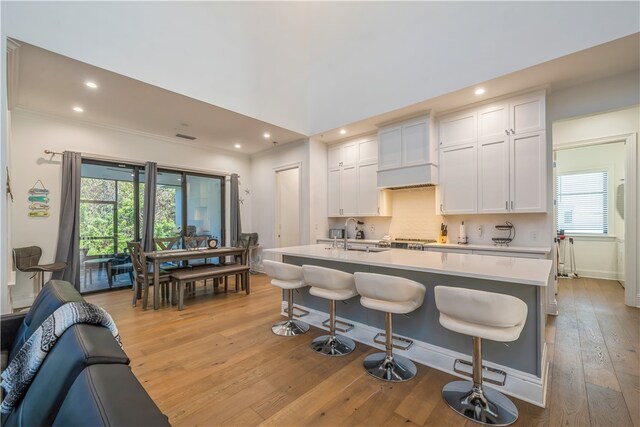 kitchen featuring light wood-type flooring, white cabinetry, a breakfast bar, and plenty of natural light