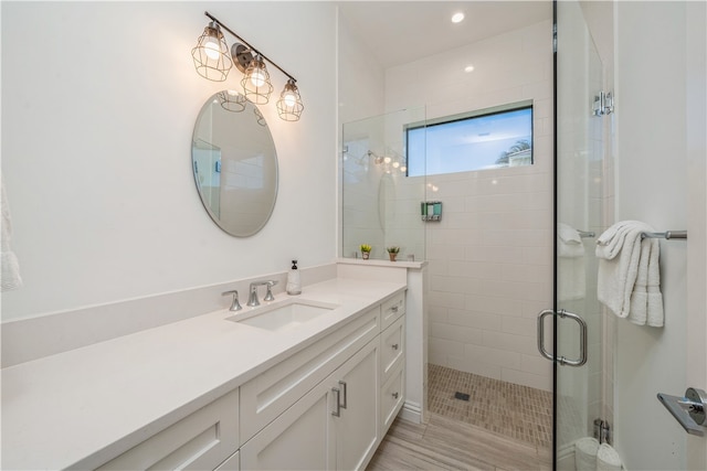 bathroom featuring walk in shower, vanity, and hardwood / wood-style flooring