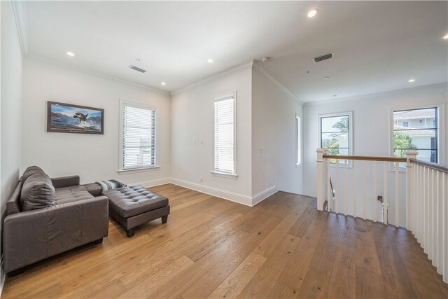 living room featuring light wood-type flooring, a wealth of natural light, and crown molding