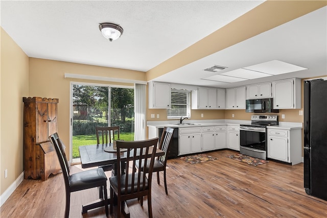 kitchen featuring white cabinets, wood-type flooring, sink, and black appliances