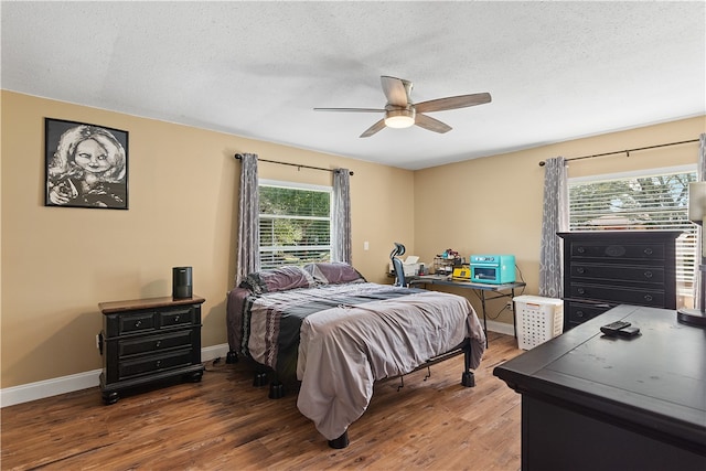 bedroom featuring dark hardwood / wood-style floors, ceiling fan, and multiple windows