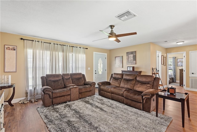 living room featuring ceiling fan, a wealth of natural light, and wood-type flooring