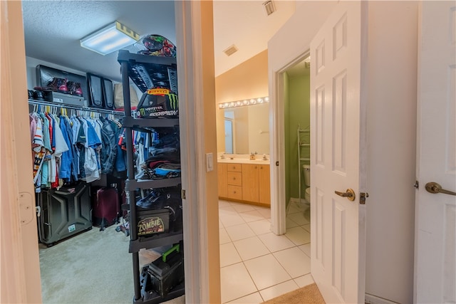 spacious closet featuring lofted ceiling, light tile patterned flooring, and sink