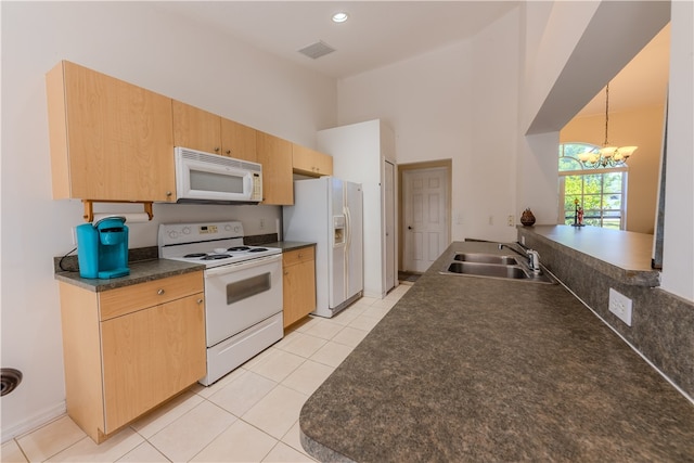 kitchen with an inviting chandelier, light tile patterned floors, sink, white appliances, and decorative light fixtures