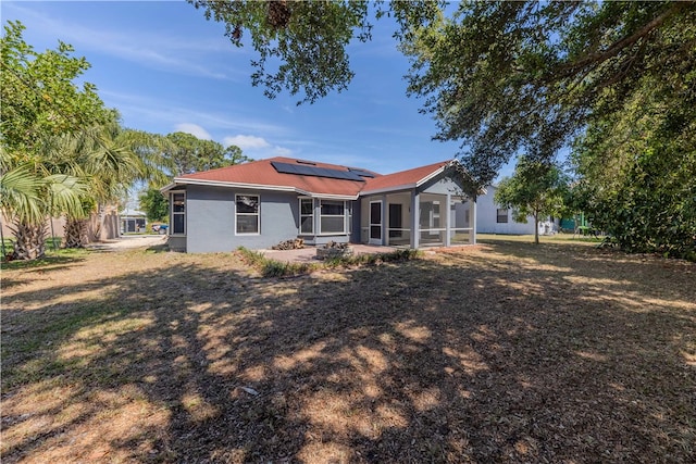 rear view of house featuring a patio, a sunroom, and solar panels