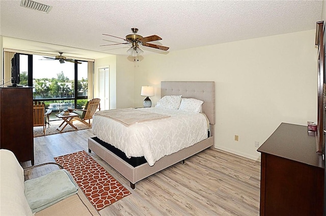 bedroom featuring ceiling fan, light hardwood / wood-style floors, a textured ceiling, and a closet