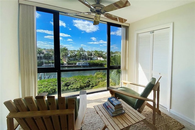 sunroom / solarium with ceiling fan and a water view