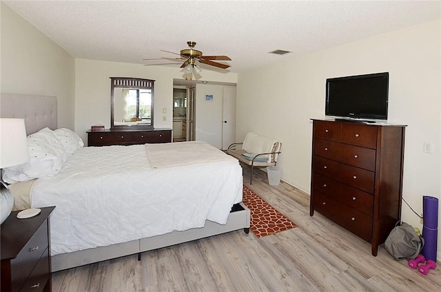 bedroom featuring ceiling fan, light hardwood / wood-style floors, and a textured ceiling