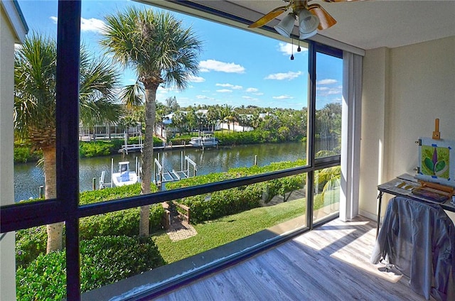 sunroom / solarium featuring a water view and ceiling fan