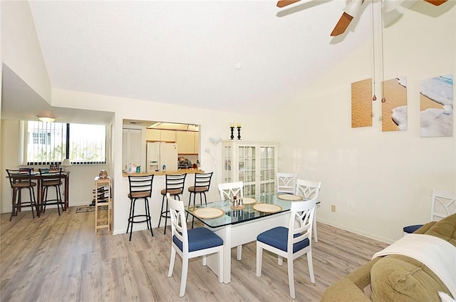 dining space with vaulted ceiling, light hardwood / wood-style flooring, and ceiling fan