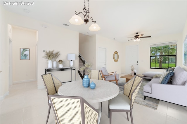 dining area with light tile patterned flooring and ceiling fan with notable chandelier