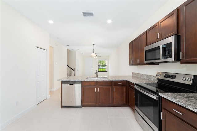 kitchen with kitchen peninsula, appliances with stainless steel finishes, sink, and light stone counters