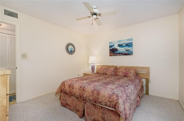 bedroom featuring light carpet, ceiling fan, and a textured ceiling