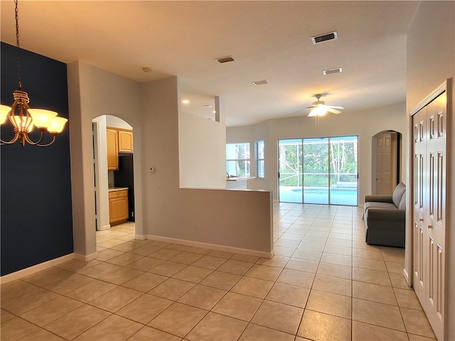 empty room with light tile patterned floors and ceiling fan with notable chandelier