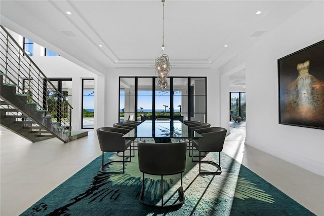 tiled dining room featuring an inviting chandelier and a raised ceiling