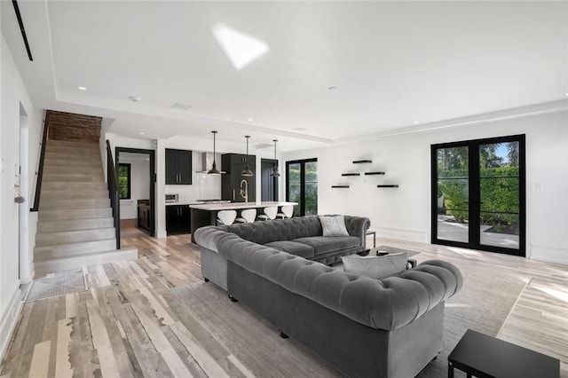 living room with light wood-type flooring, sink, and french doors