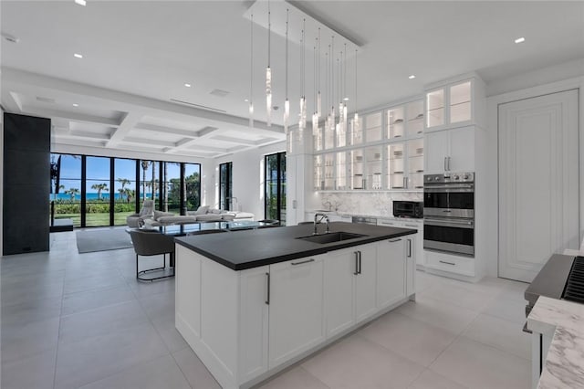 kitchen with coffered ceiling, white cabinets, sink, decorative light fixtures, and stainless steel double oven