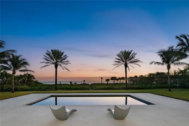 pool at dusk featuring a water view