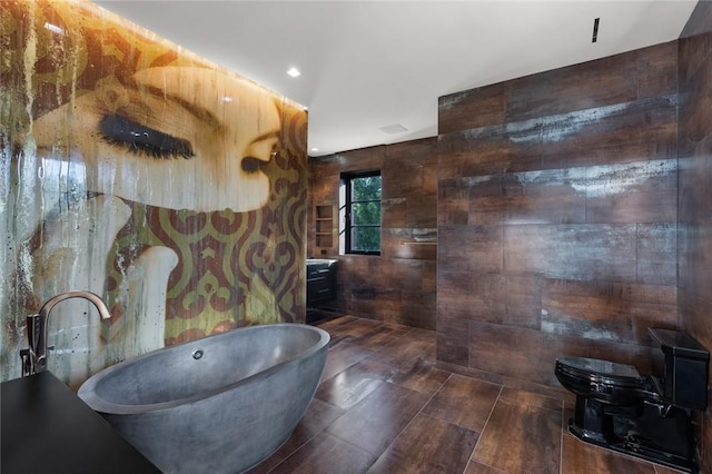 bathroom with vanity, a tub to relax in, and toilet