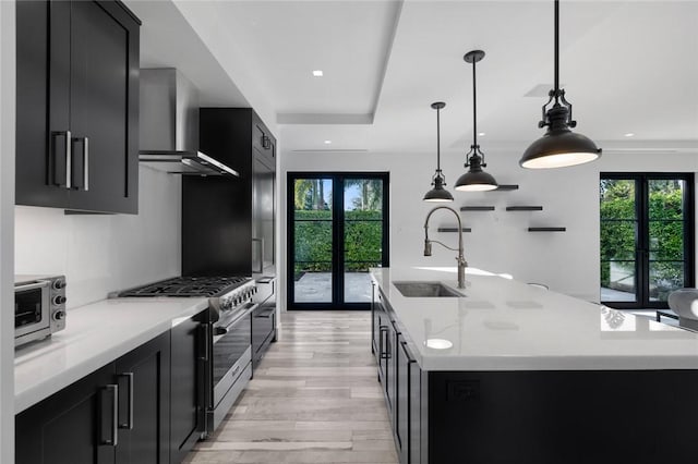 kitchen with french doors, high end stainless steel range oven, a kitchen island with sink, and sink