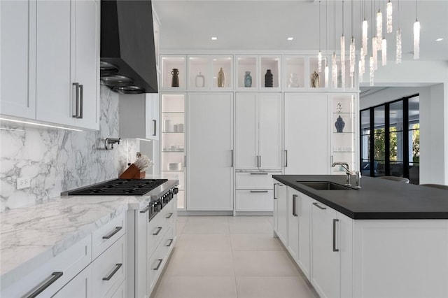 kitchen with white cabinetry, sink, a kitchen island, and wall chimney range hood