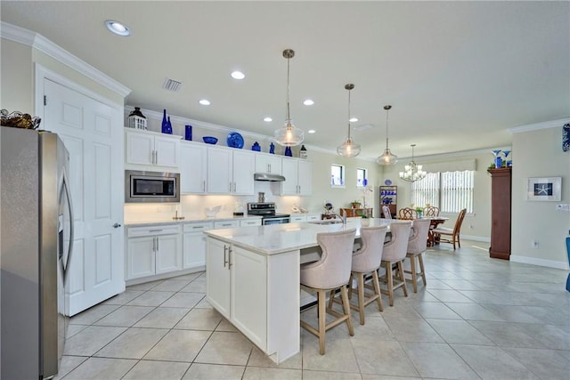 kitchen with decorative light fixtures, a center island with sink, white cabinets, and appliances with stainless steel finishes