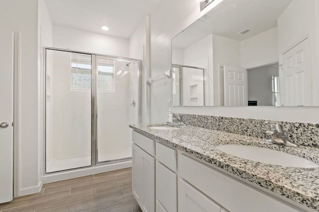 bathroom featuring hardwood / wood-style flooring, a shower with door, and vanity