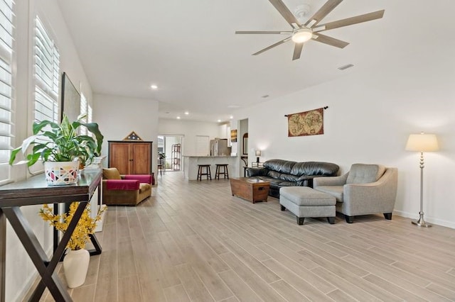 living room with light hardwood / wood-style floors and ceiling fan