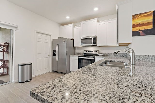 kitchen with white cabinets, light hardwood / wood-style floors, stainless steel appliances, and sink