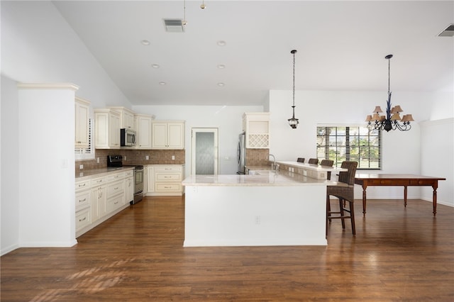 kitchen with pendant lighting, dark hardwood / wood-style flooring, stainless steel appliances, and cream cabinets