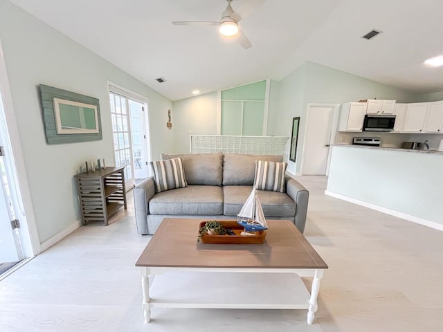 living room featuring ceiling fan, light hardwood / wood-style floors, and vaulted ceiling