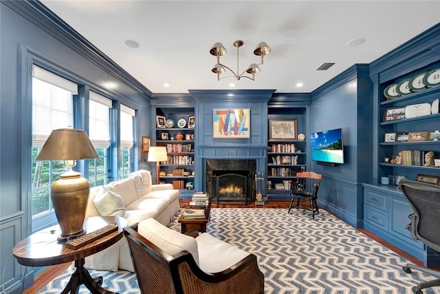 living room with ornamental molding, wood-type flooring, a high end fireplace, and built in shelves