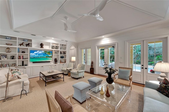 living room featuring lofted ceiling, ceiling fan, ornamental molding, built in shelves, and french doors