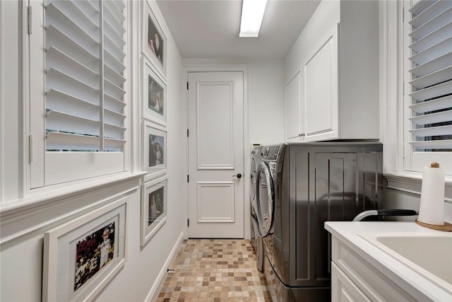 clothes washing area with cabinets and separate washer and dryer