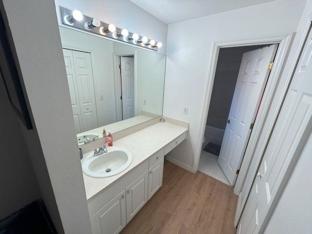 full bath featuring wood finished floors, vanity, and baseboards