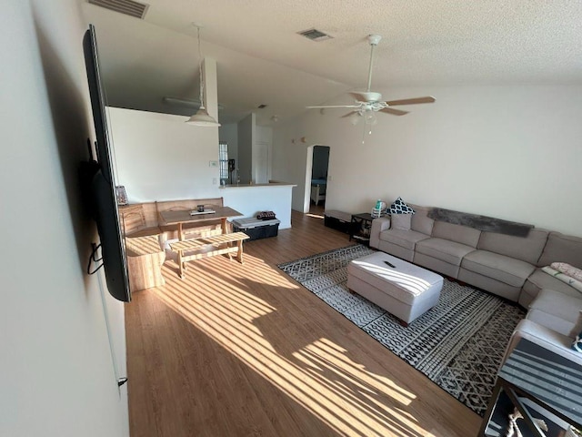 living room featuring lofted ceiling, visible vents, ceiling fan, a textured ceiling, and wood finished floors