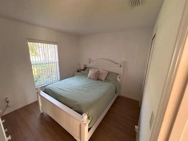 bedroom with visible vents, a textured ceiling, and wood finished floors