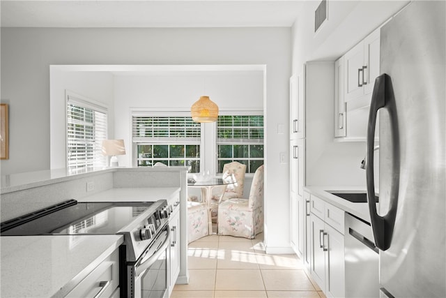 kitchen featuring light stone countertops, stainless steel appliances, light tile patterned floors, white cabinets, and hanging light fixtures