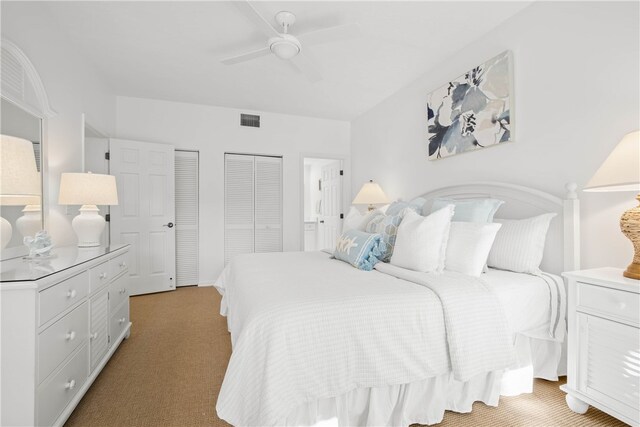 bedroom featuring light carpet, ceiling fan, and two closets